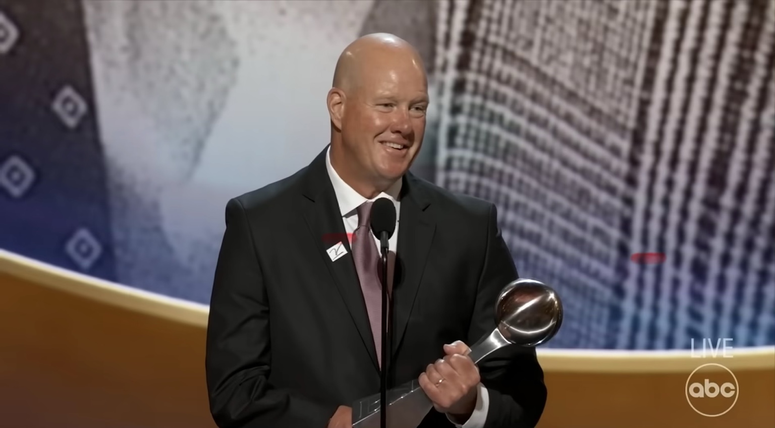 Jim Abbott smiling on stage while holding his award